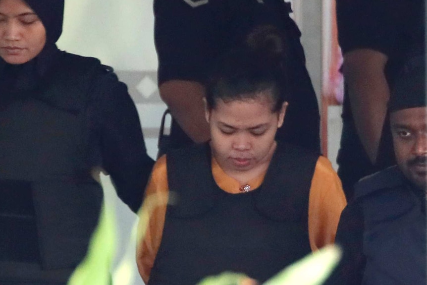 Indonesian Siti Aisyah looks down as she is escorted by a police officer