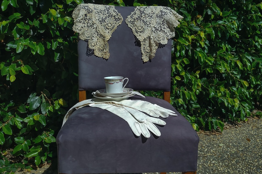 Fine dining chair with a tea-cup and saucer and evening gloves sitting on it