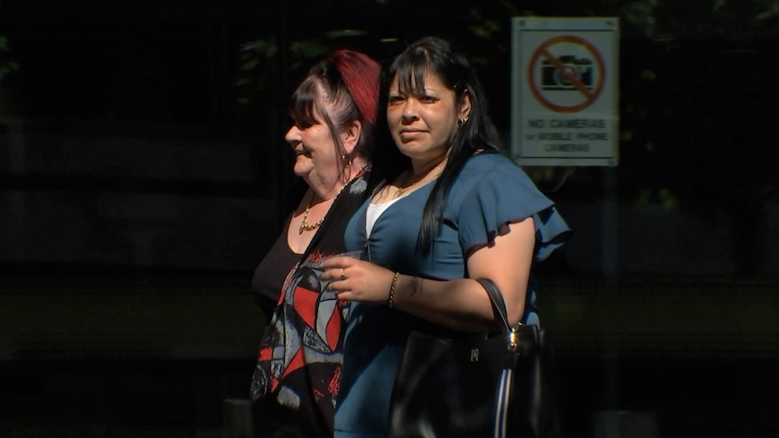 A woman walking into court with another woman.