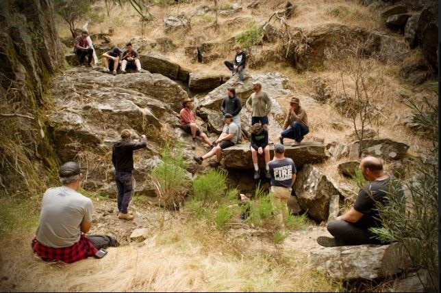 A group of young people sitting around a tree in daylight