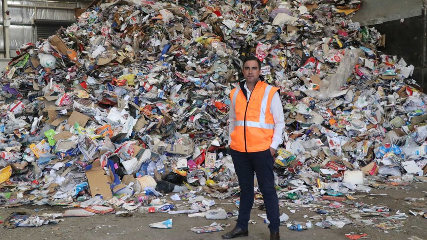 NAWMA Ceo Adam Faulkner in front of a big rubbish pile