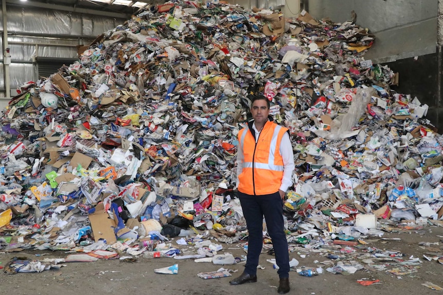 NAWMA Ceo Adam Faulkner in front of a big rubbish pile