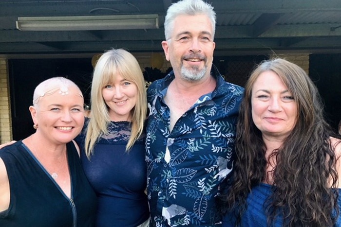 Cancer patient Belinda Cosgrove (left) stands in a hug with her sisters and brother.