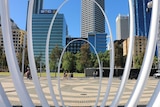 Metal oval poles the frame the Perth skyline in the background.