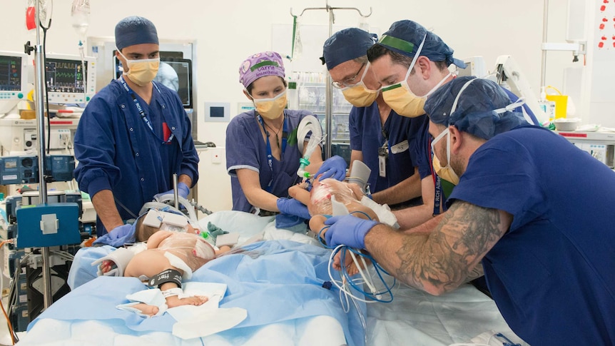 A group of medics with two separate children on an operating table.