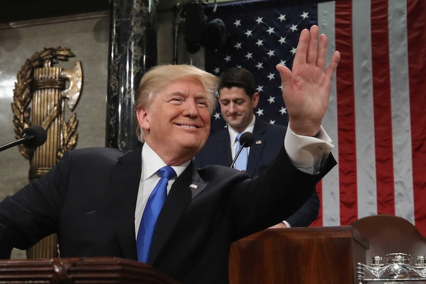 US President Donald Trump waves to the crowd inside the House Chamber