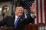 US President Donald Trump waves to the crowd inside the House Chamber