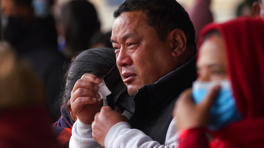 Mourners weep as they wait to claim their dead