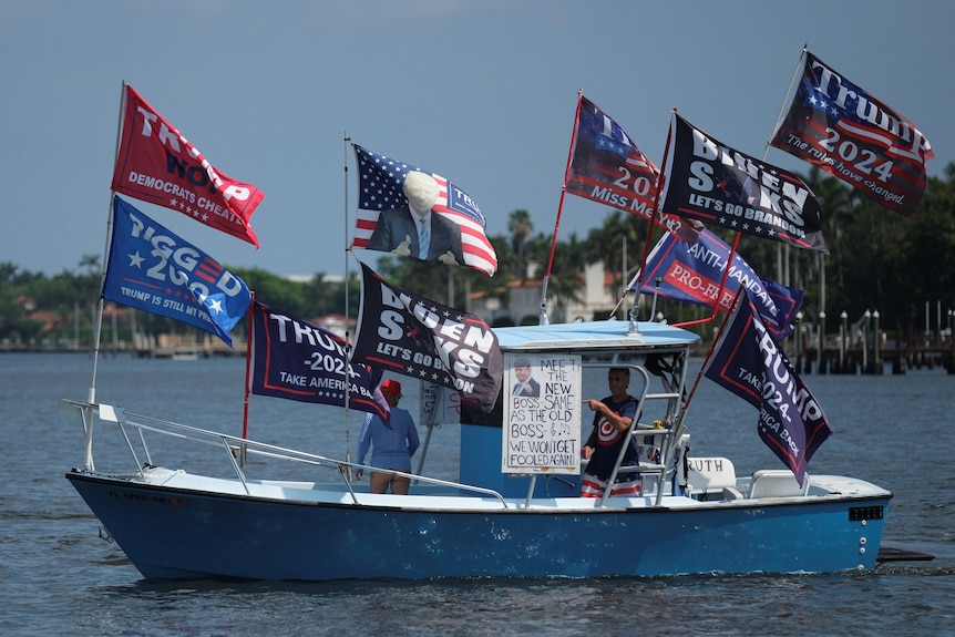 People on a boat with multiple Trump flags flying. 