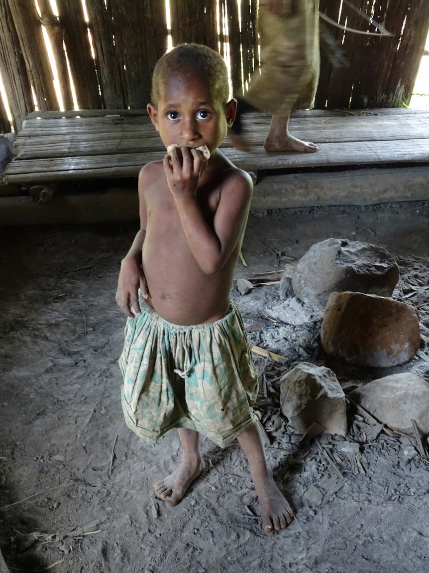 A child stands holding food