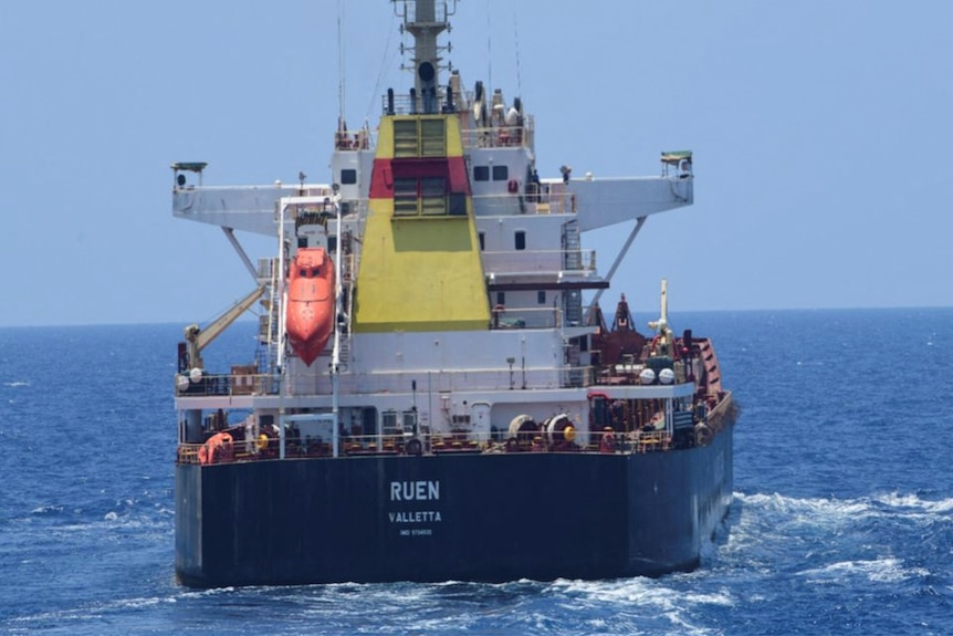 A cargo ship is seen from behind with the life raft visible. 