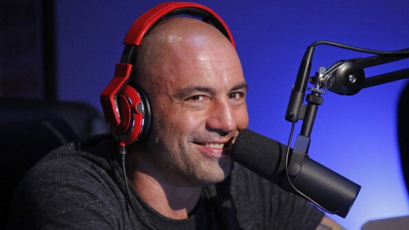A bald man with red headphone speaks into a microphone