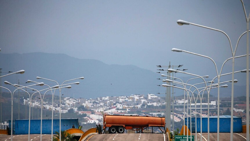 Truck containers are spread across a highway as soldiers stand guard at the Venezuelan border.