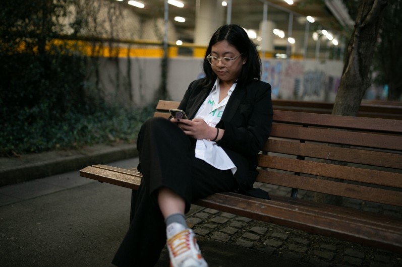 A woman on a bench looking at a phone.