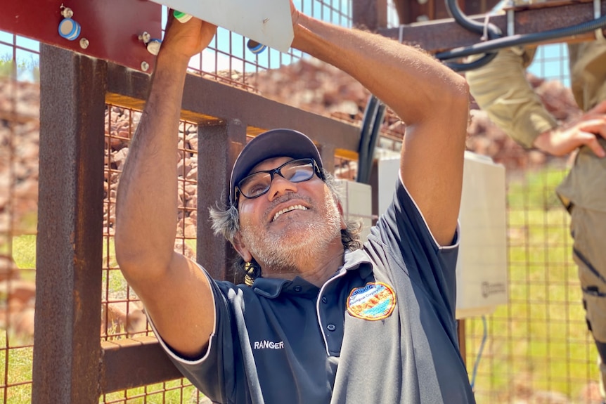 A man collecting samples from an air quality monitoring station on the Burrup Peninsular