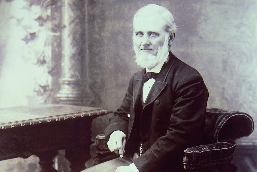 Very old monochrome portrait, man in suit with beard seated at desk