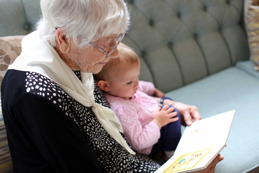 Baby Isabella sits on Joyce's lap while she reads to her.