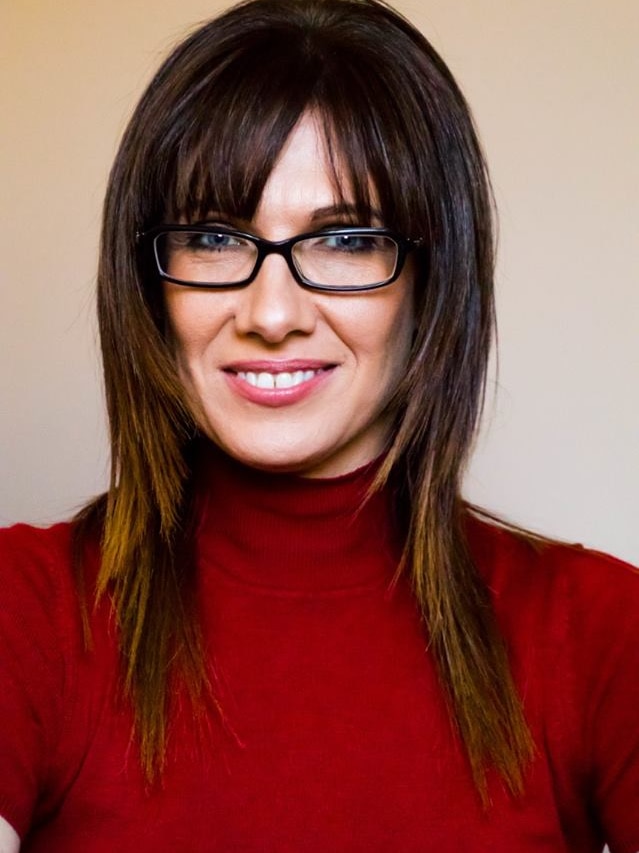 A profile shot of a smiling Renee Ellis wearing glasses and a red top.