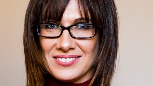 A profile shot of a smiling Renee Ellis wearing glasses and a red top.