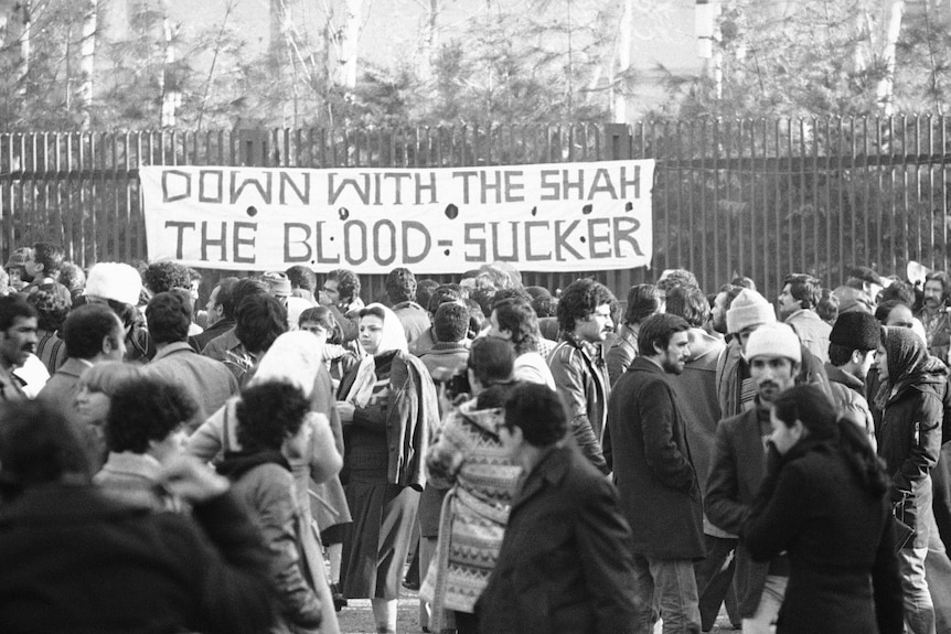 Sign over crowd reads "Down with the Shah the blood sucker".