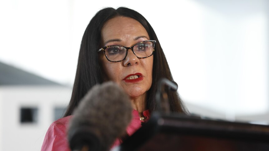 Linda Burney at a lectern with a large microphone in front of her. 
