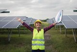 Woman with arms outstretched standing in front of solar panels