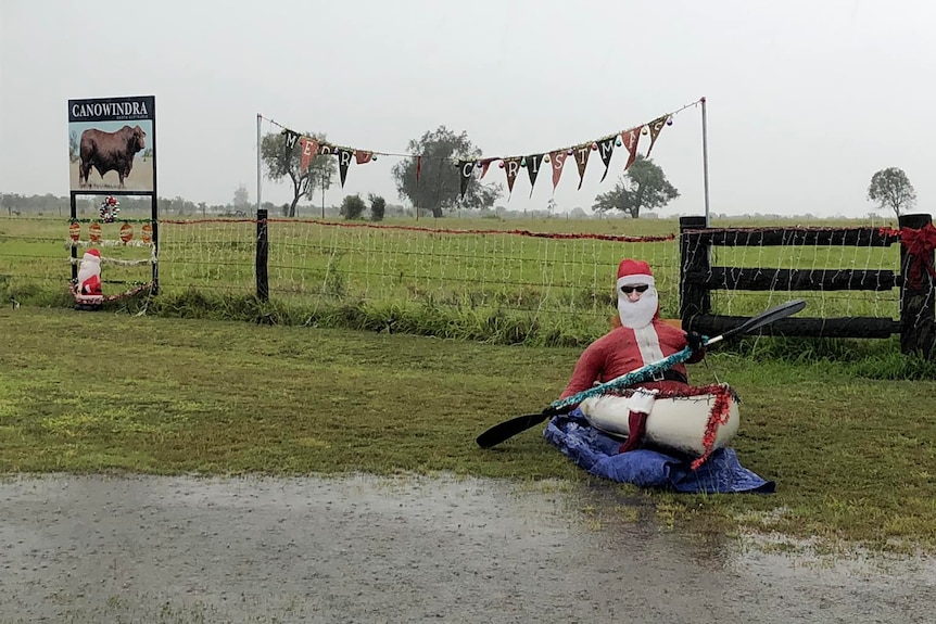 A blow up santa in a canoe with a small amount of water pooled 