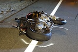 A crashed motorbike lies on the side of the road.