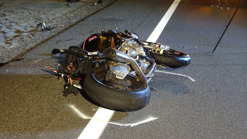 A crashed motorbike lies on the side of the road.