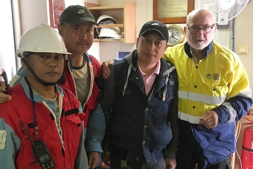 Sailors in high vis and hard hats.