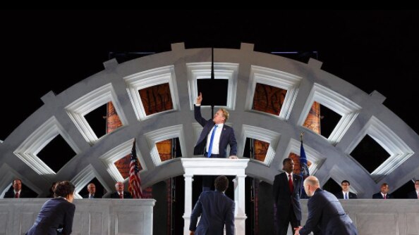 Donald Trump-like Julius-Caesar raises his hand in the air during the Shakespeare in the Park production