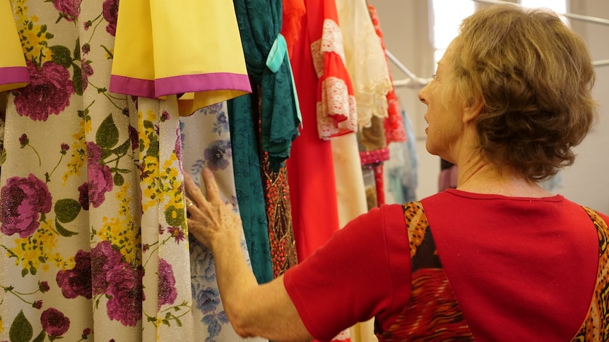 Woman looks at colour dresses hanging.
