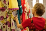 Woman looks at colour dresses hanging.