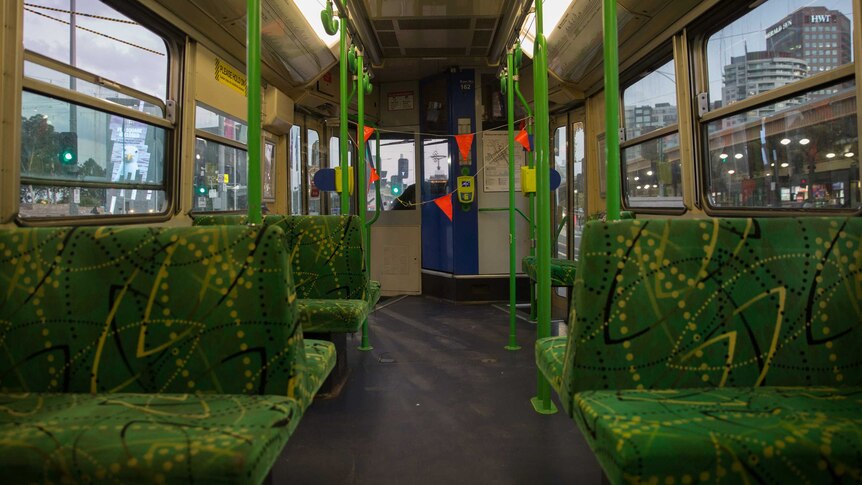 Empty green seats leading to the tram driver seats, cordoned off by orange flags