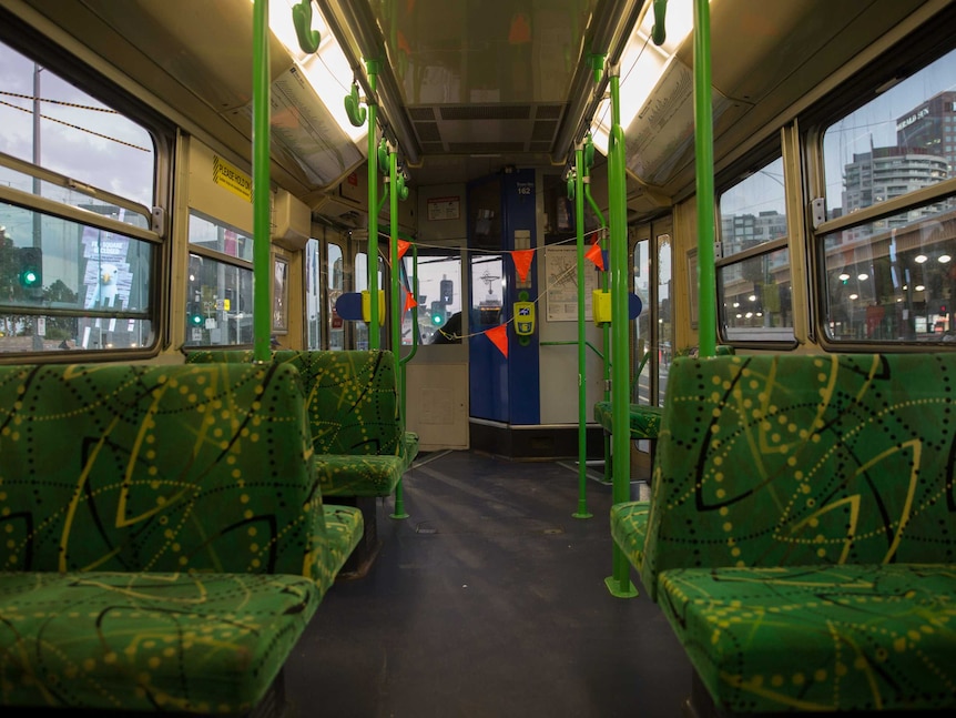 Empty green seats leading to the tram driver seats, cordoned off by orange flags