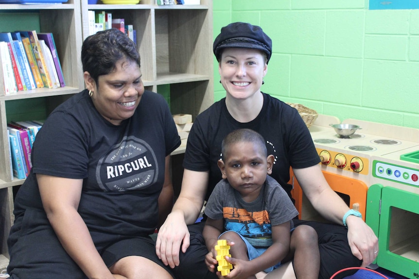 Two women and a young Indigenous boy sit together.