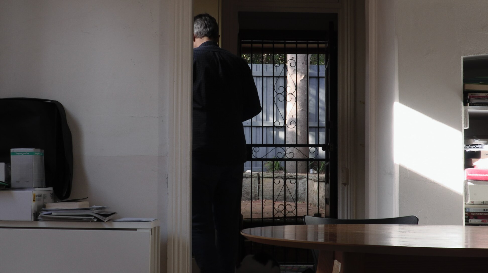A rear view of a man standing in a house.