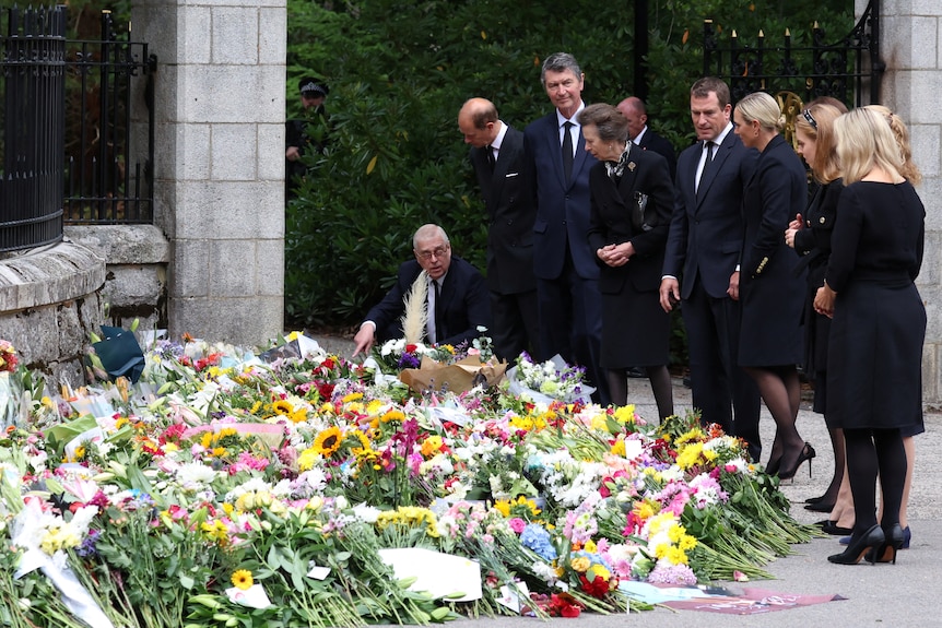 Members of the royal family stand by floral tributes outside castle gates. 