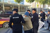 Police escort anti-American protester, surnamed Li, away from the US embassy in Beijing