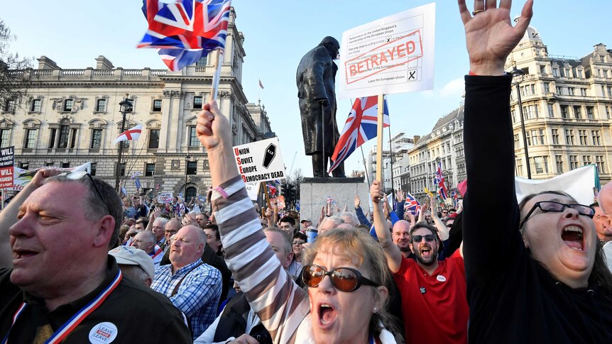 A group of protesters hold their hands in the air in front of a statue of Winston Churchill
