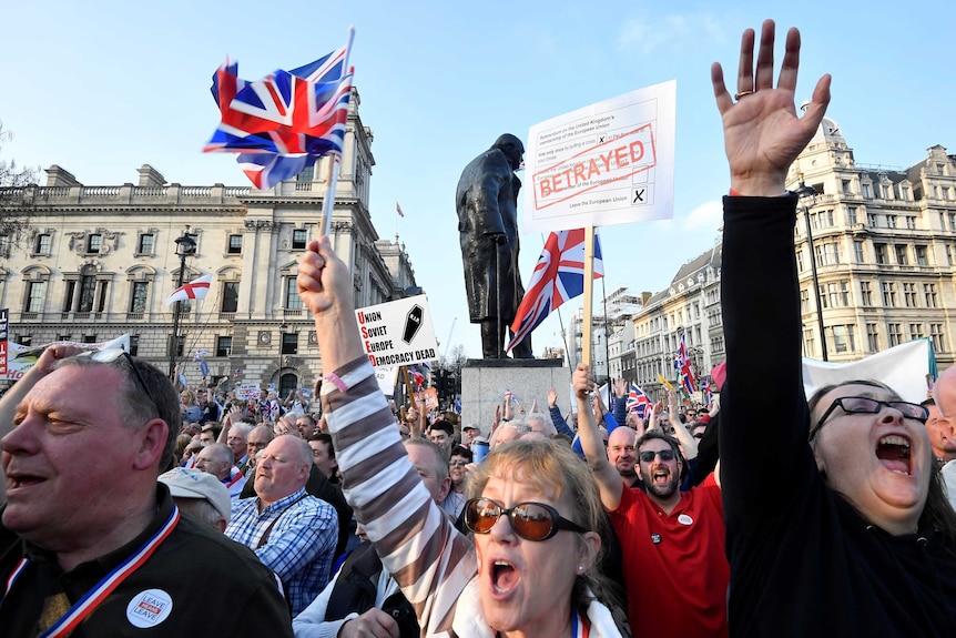 A group of protesters hold their hands in the air in front of a statue of Winston Churchill