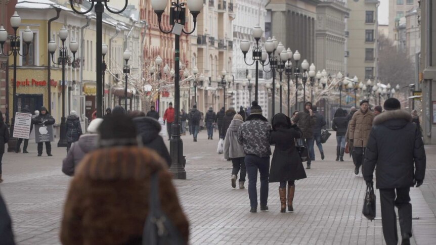 Pedestrians walk along a Moscow high street