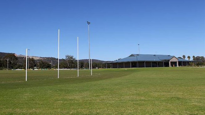 A sports oval with football goals and a club room.