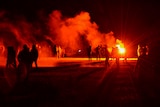 Youths stand in a field during clashes as police tried to break up an unauthorized rave party