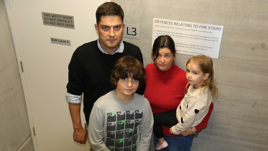 Mark Jones, his wife, and his children stand at the foot of a stairwell.