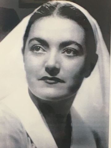 A black and white portrait of a woman in a nurse uniform and veil-like head covering.
