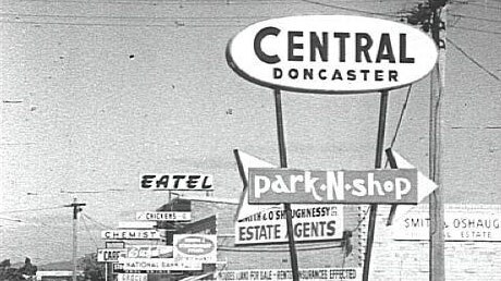 Old photo of city street with many street signs, large sign reads 'Central Doncaster'