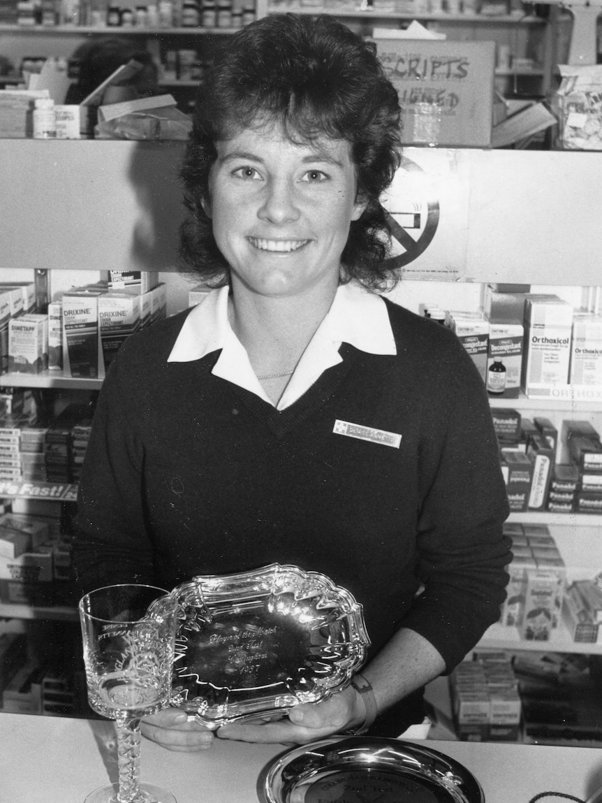 Denise Annetts smiles for the camera while holding a silver plate.