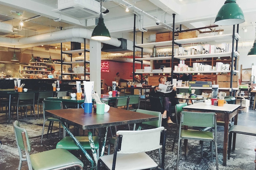 Man sitting in an empty cafe reading a magazine