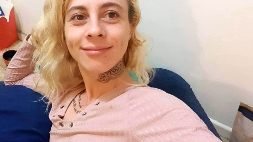A young blonde woman with a tattoo on her neck.